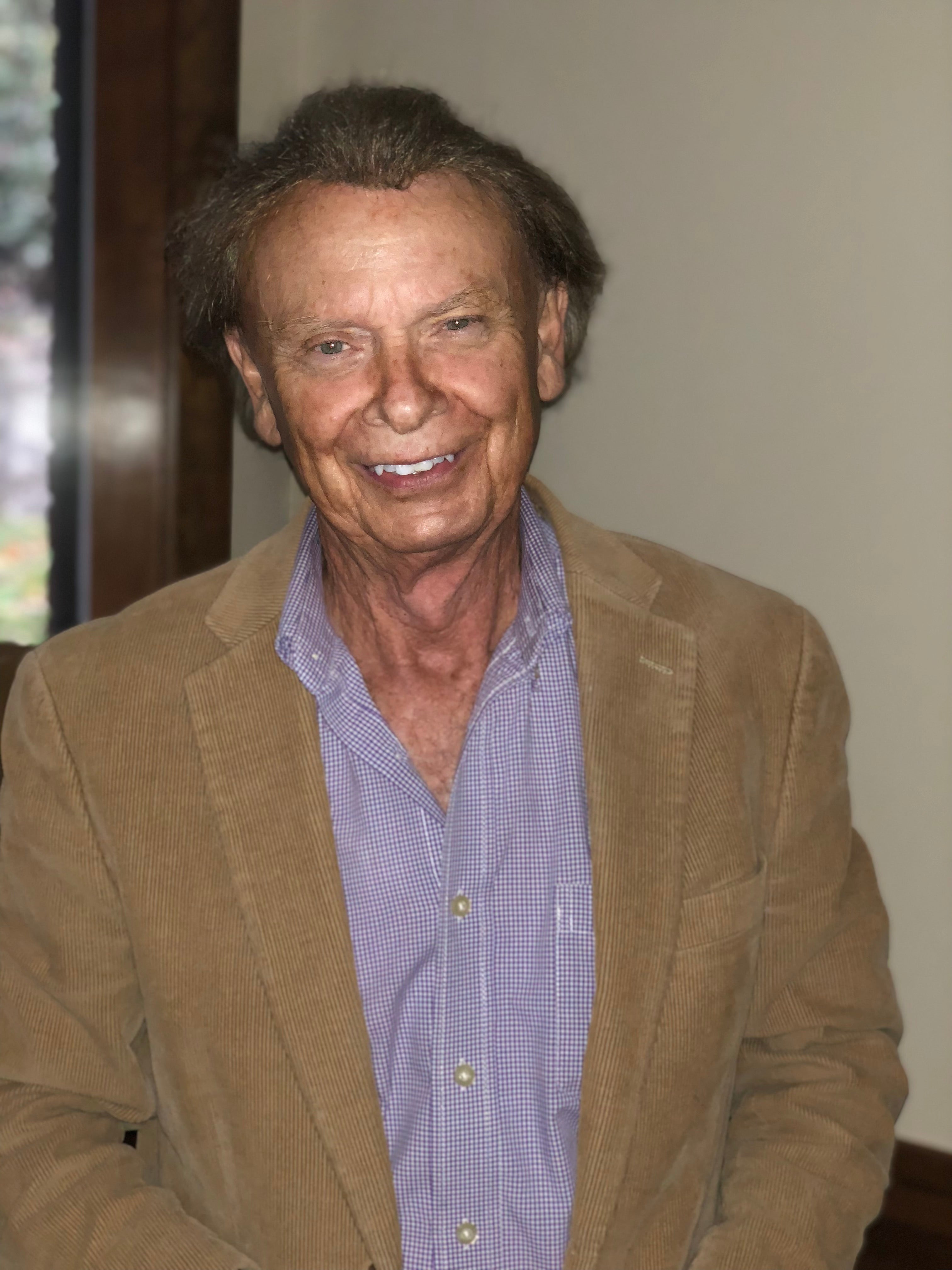 Walter Smith, founder of Impression Products, smiling & wearing a tan blazer over a checkered shirt, showing his legacy.