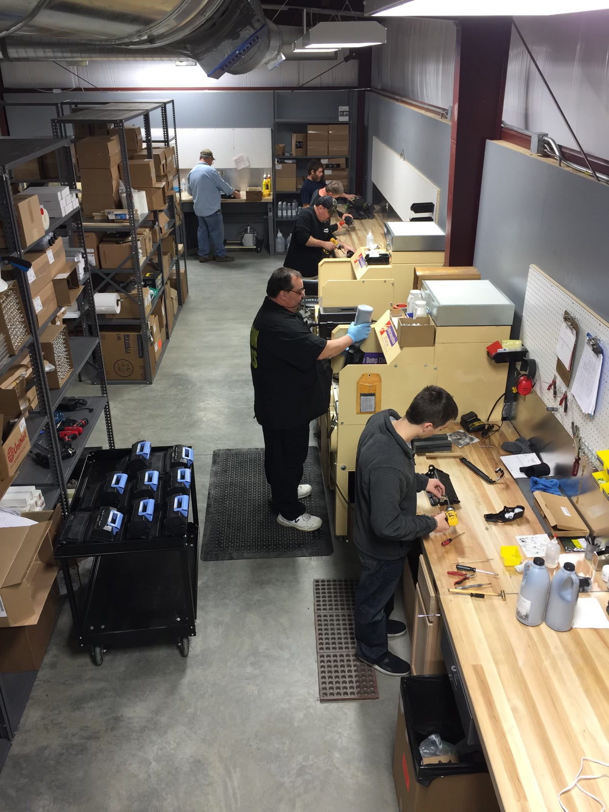 Team members working in a production facility assembling and testing printer cartridges, showcasing efficient production.
