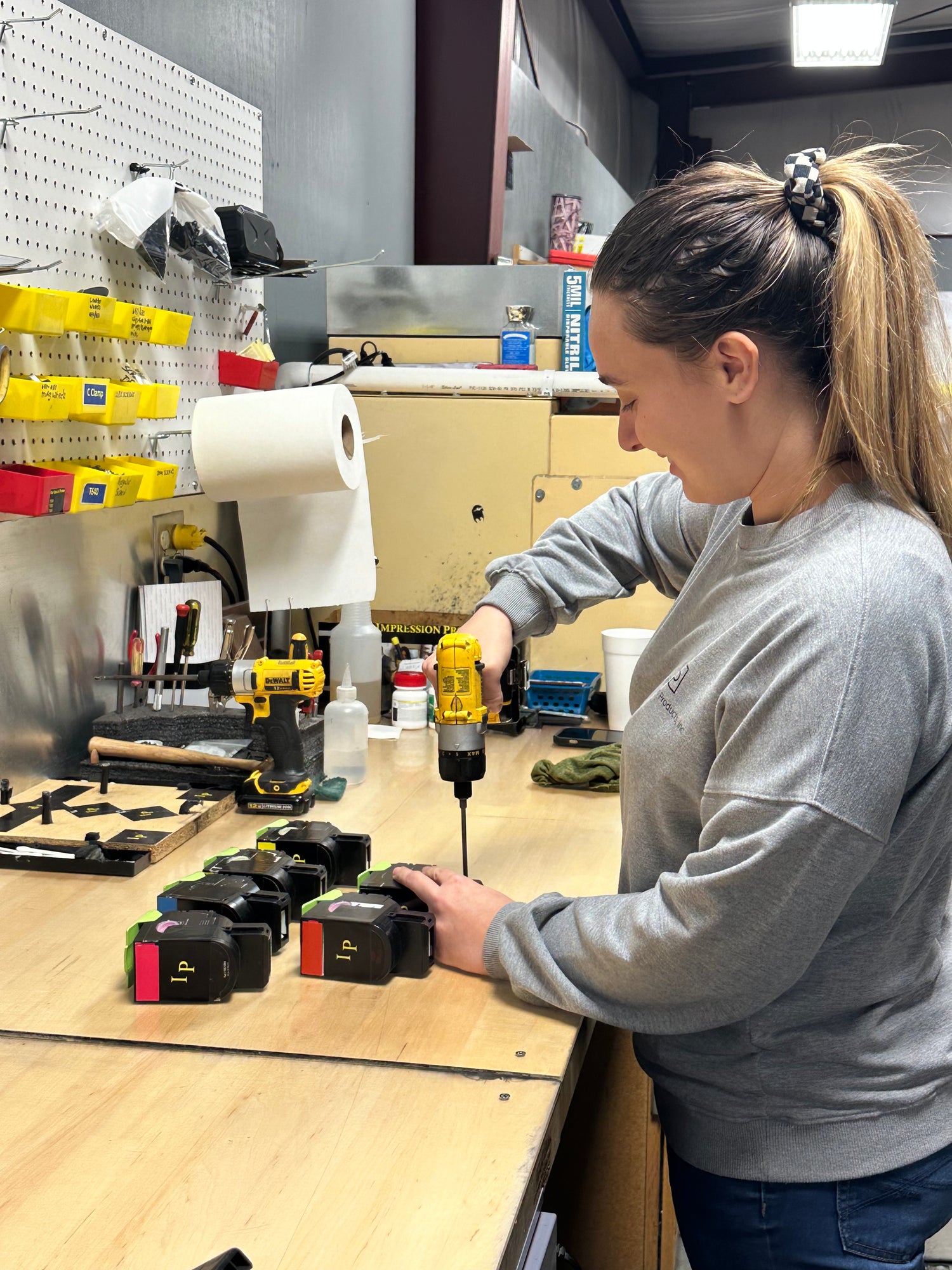 Technician working on remanufacturing printer cartridges at a workstation equipped with tools and supplies.