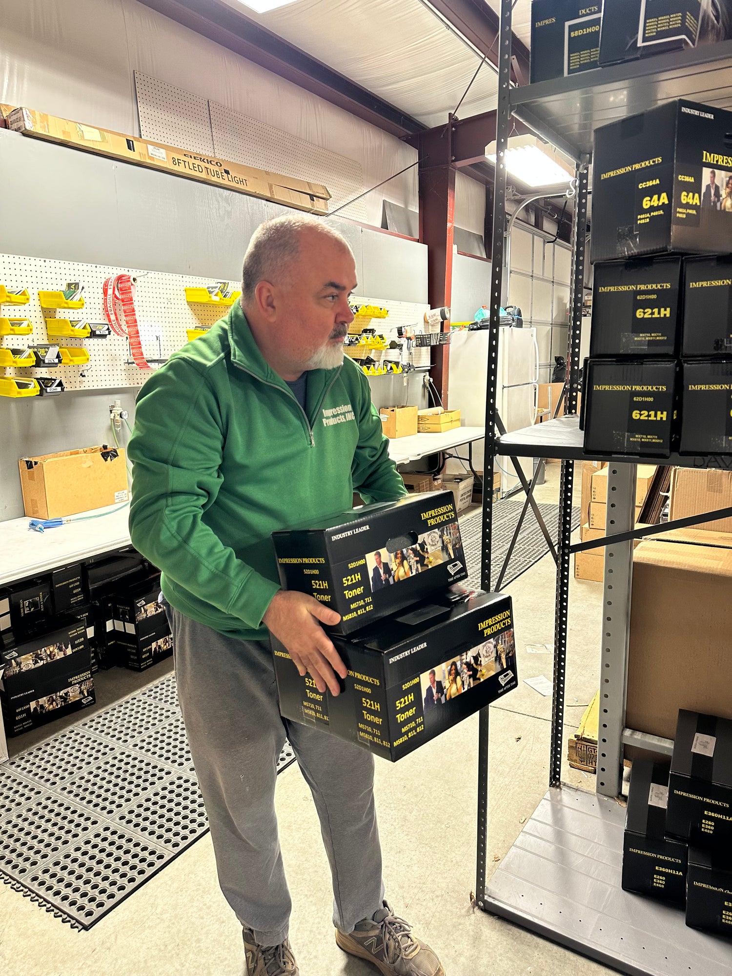 Impression Products team member organizing toner cartridges in a warehouse, demonstrating efficient inventory management.